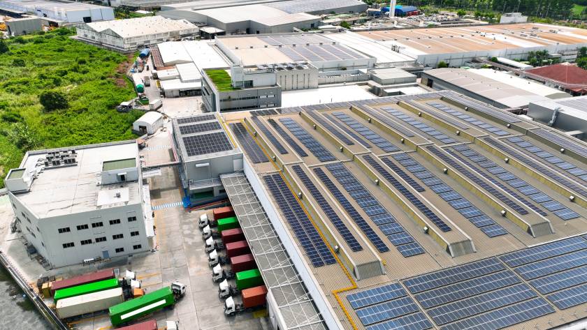 Solar-powered warehouse facility with freight trucks at loading docks. Eco-friendly logistics